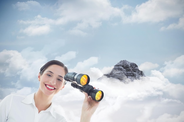Lächelnde Geschäftsfrau mit Fernglas gegen Berggipfel durch die Wolken