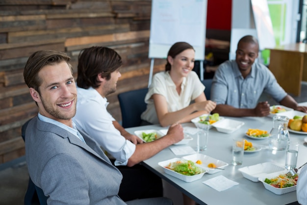 Lächelnde Geschäftsleute, die Mahlzeit im Büro haben