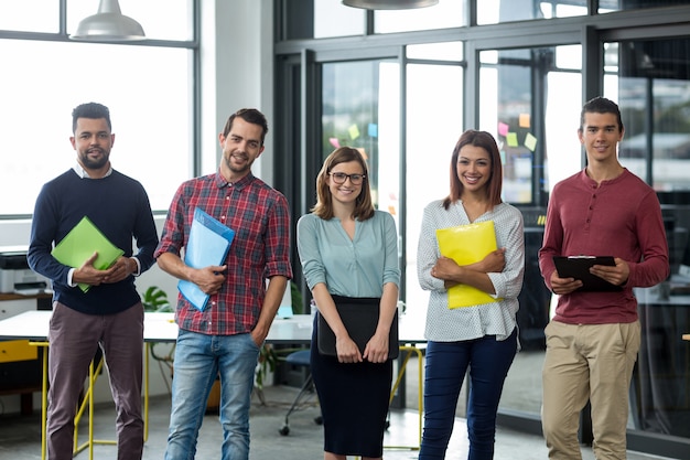 Foto lächelnde geschäftsleute, die mit datei und zwischenablage im büro stehen