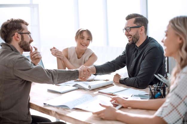 Lächelnde Geschäftspartner, die sich bei einem Geschäftstreffen die Hände schütteln