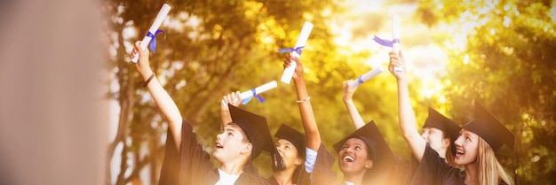 Lächelnde Graduiertenschulkinder, die mit Gradrolle im Campus stehen