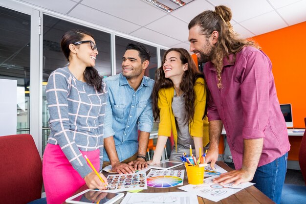 Lächelnde Grafikdesigner, die über Fotos am Schreibtisch arbeiten