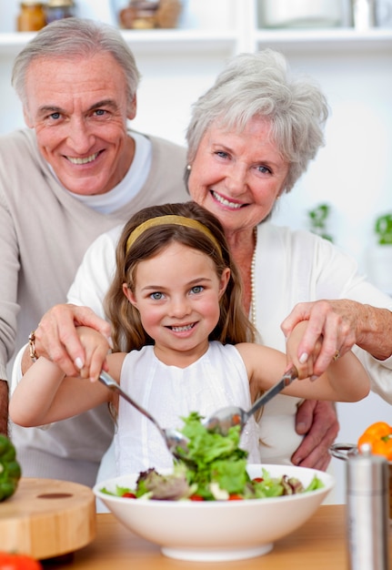 Lächelnde Großeltern, die einen Salat mit Enkelin essen