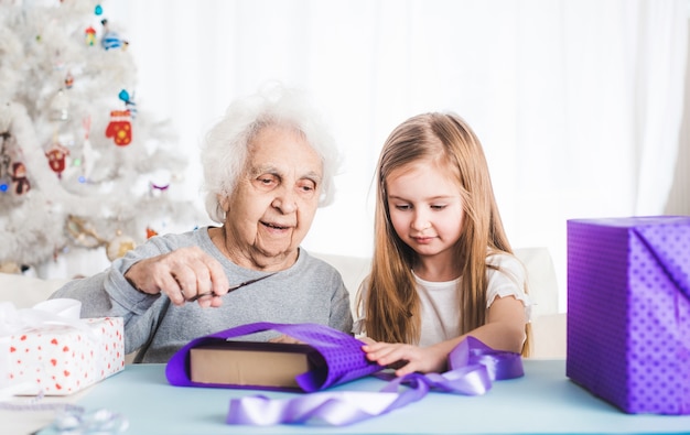 Lächelnde Großmutter mit Enkelin, die Geschenke an Weihnachten verziert