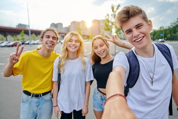 Lächelnde Gruppe von Teenagern, die ein Selfie machen, glückliche vier Teenager, die in die Kamera schauen