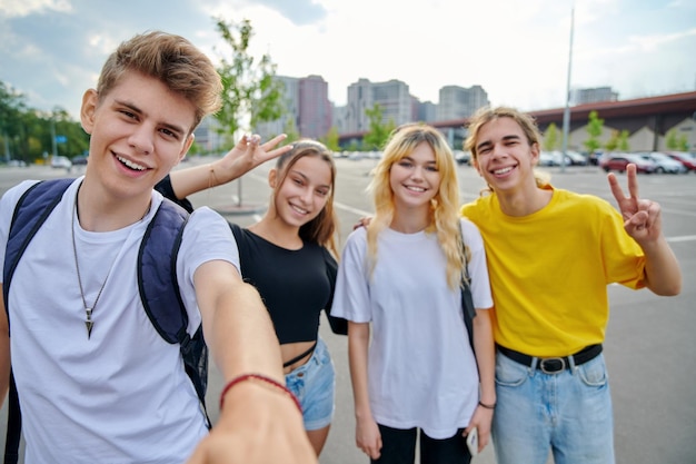 Lächelnde Gruppe von Teenagern, die ein Selfie machen, glückliche vier Teenager, die in die Kamera schauen