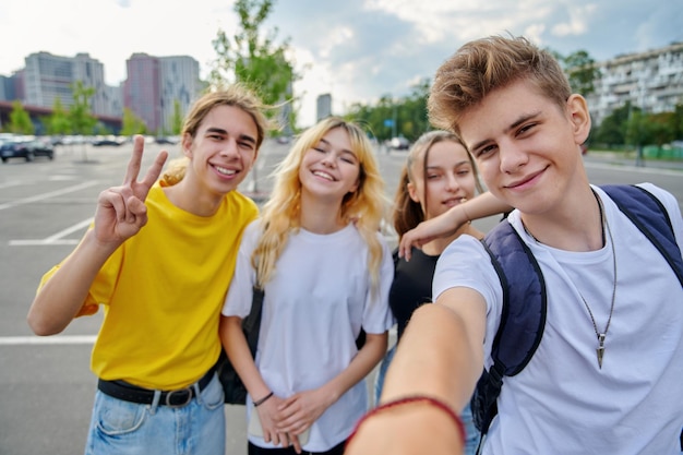 Lächelnde Gruppe von Teenagern, die ein Selfie machen, glückliche vier Teenager, die in die Kamera schauen