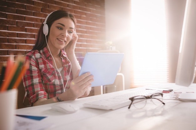 Lächelnde hörende Exekutivmusik auf digitaler Tablette