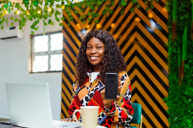 lächelnde junge afrikanische Geschäftsfrau mit Handy mit leerem Bildschirm
