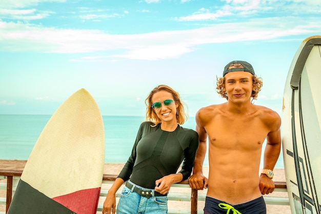 Lächelnde junge aktive Paar-Surfer, die sich nach dem Sport mit Surfboard Healthy Lifestyle Extreme Water Sports am Strand entspannen