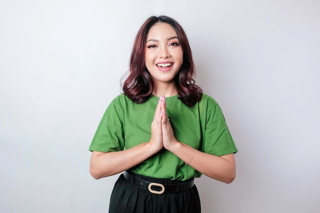 Lächelnde junge asiatische Frau, die den traditionellen Gruß lokalisiert über weißem Hintergrund gestikuliert