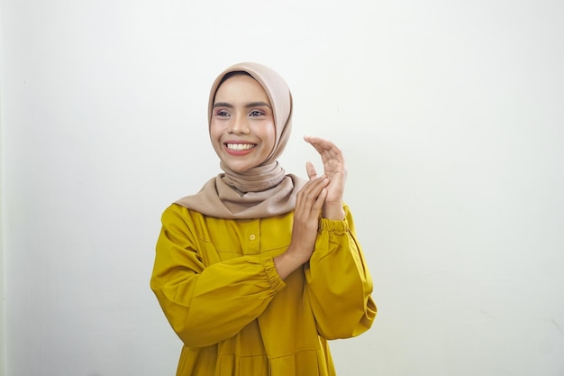 Lächelnde junge asiatische muslimische Frau fühlt sich isoliert vor weißem Hintergrund zuversichtlich und fröhlich