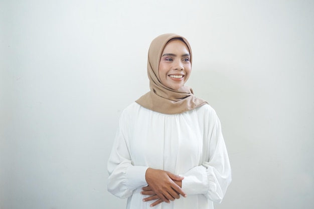 Lächelnde junge asiatische muslimische Frau gestikuliert Eid Mubarak-Gruß isoliert auf weißem Hintergrund