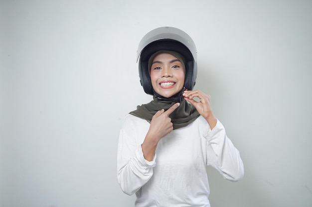 Lächelnde junge asiatische muslimische Frau mit Motorradhelm isoliert auf weißem Hintergrund