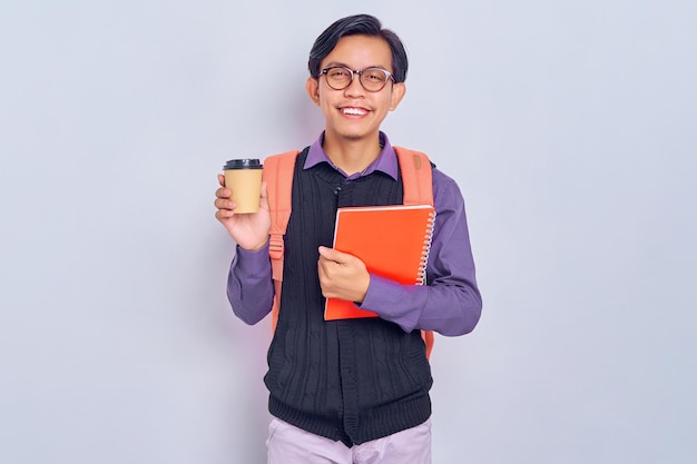 Lächelnde junge asiatische Studenten, die lässige Kleidung tragen, mit Rucksäcken, die Bücher und eine Kaffeetasse halten, die auf grauem Hintergrund isoliert sind Bildung im High-School-University-College-Konzept