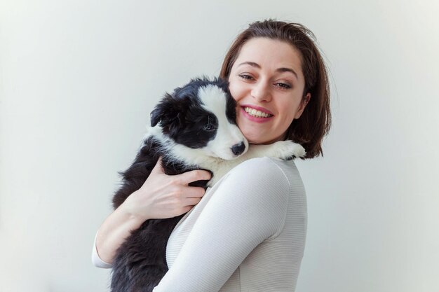 Lächelnde junge attraktive Frau umarmt süßen Hündchen Border Collie isoliert auf weißem Hinterg...