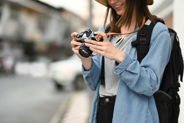 Lächelnde junge Fotografin mit Digitalkamera, die in der Stadtstraße steht Blogger-Urlaubs- und Reisekonzept