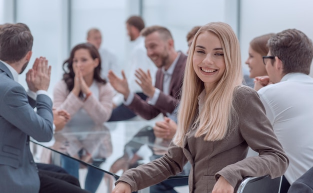 Foto lächelnde junge frau, die am tisch im konferenzraum sitzt