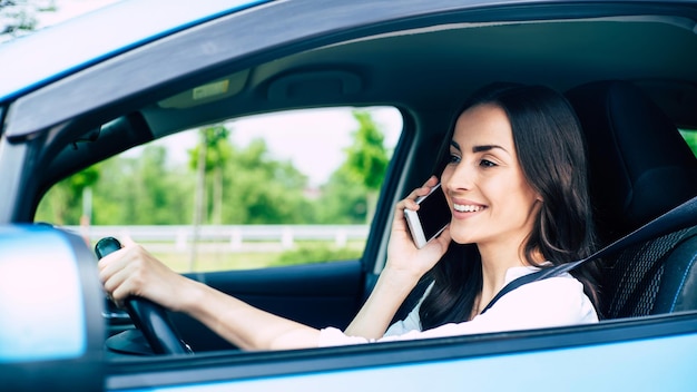 Lächelnde junge Frau, die beim Autofahren telefoniert