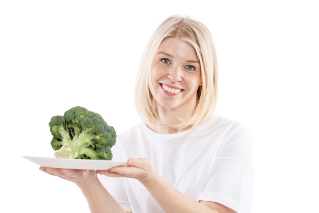 Lächelnde junge Frau, die eine Platte des Brokkolis in ihren Händen anhält. Vegetarismus und Rohkost. Gesundheit und richtige Ernährung. Isoliert auf weißem hintergrund