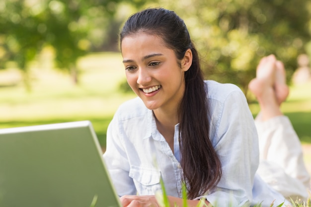 Lächelnde junge Frau, die Laptop im Park verwendet