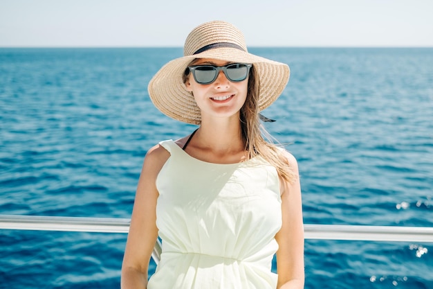 Lächelnde junge Frau, die während der Sommerferien auf einem Boot steht