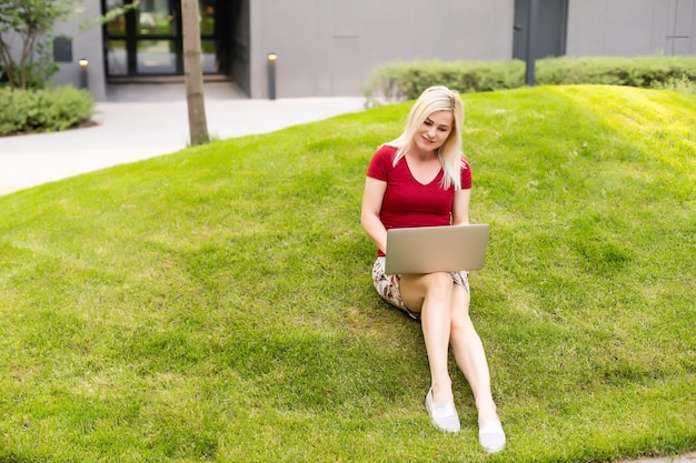 lächelnde junge Frau im Park mit Laptop