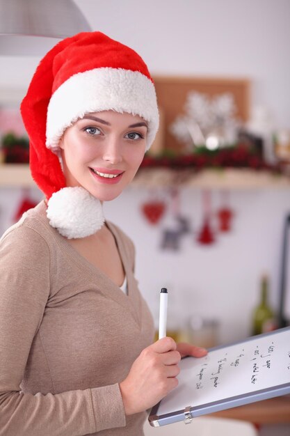Lächelnde junge Frau in der Küche lokalisiert auf Weihnachtshintergrund