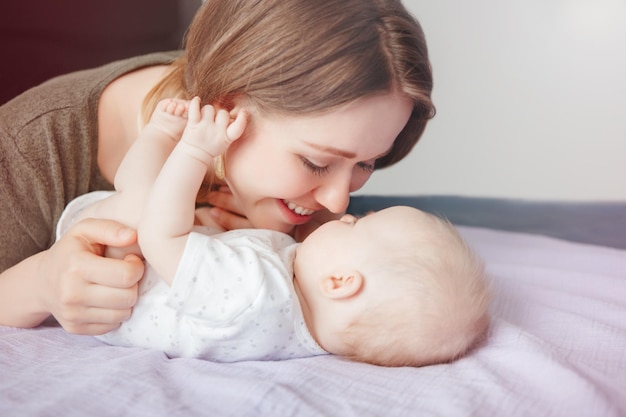 Lächelnde junge Frau mit Baby im Schlafzimmer zu Hause