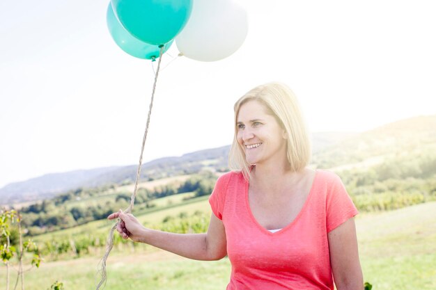 Lächelnde junge Frau mit Ballons gegen den Himmel