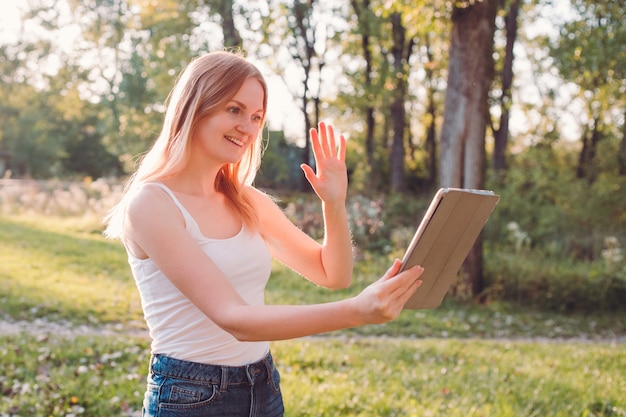 Lächelnde junge Frau mit digitaler Tablette. Kommunikationskonzept. Moment der Freizeit am Sommertag.