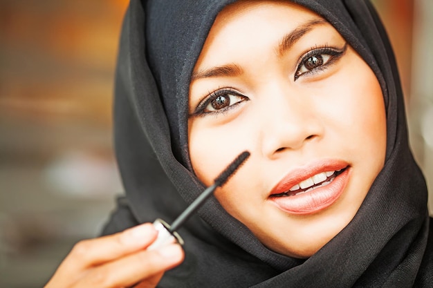 Lächelnde junge Frau mit Make-up und Hijab