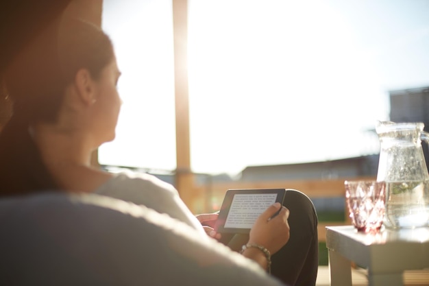 Lächelnde junge Frau sitzt auf Sofa mit Touchpad