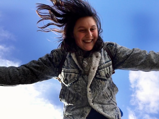 Lächelnde junge Frau springt gegen den Himmel