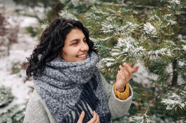 Lächelnde junge Frau steht in einem frostigen verschneiten Winterpark.