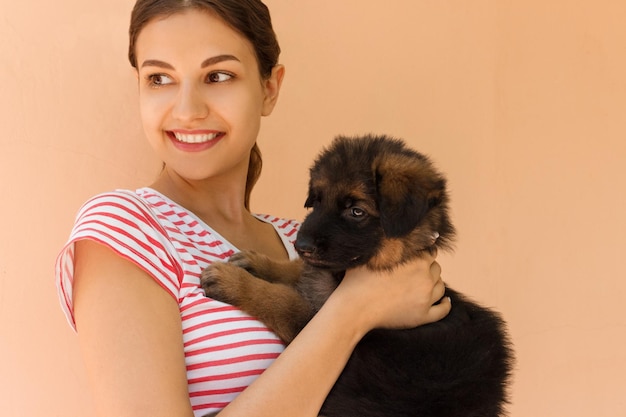 Lächelnde junge Frau trägt einen Hund, während sie an der Wand steht