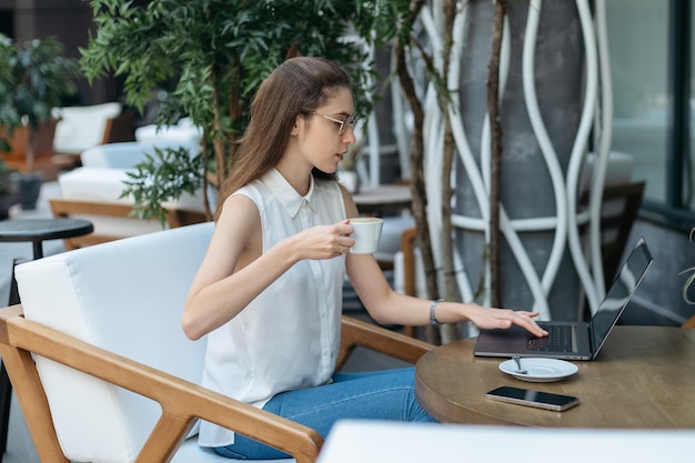 Lächelnde junge Frau trinkt Kaffee in einem gemütlichen Café