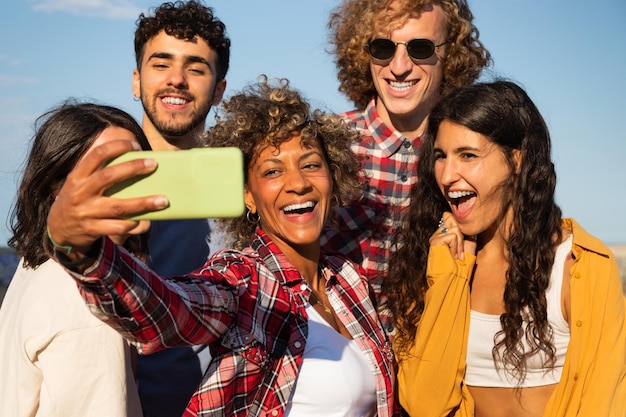 Lächelnde junge gemischtrassige Freunde machen Selfies zusammen mit dem Smartphone im Freien