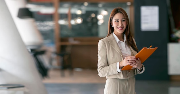 Lächelnde junge Geschäftsfrau, die in die Kamera schaut, während sie im Coworking Space steht