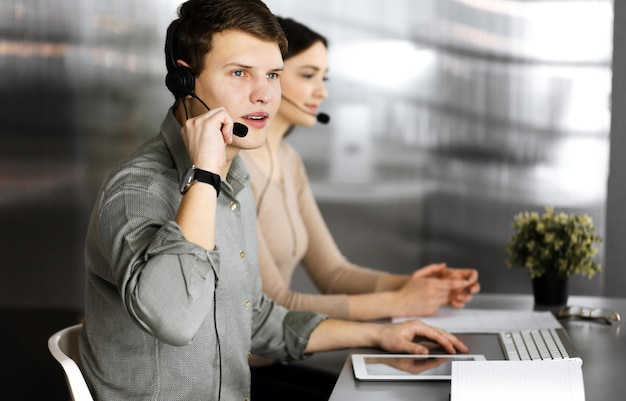 Lächelnde junge Geschäftsleute und Programmierer überprüfen einige Daten auf dem Computer, während sie in einem modernen Büro zusammensitzen Fokus auf den Menschen Konzept der erfolgreichen Unternehmensgründung