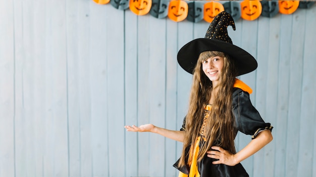 Foto lächelnde junge hexe, die halloween-kostüm zeigt