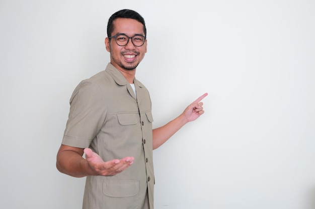 Lächelnde junge indonesische Lehrerin, die auf eine weiße Tafel dahinter zeigt