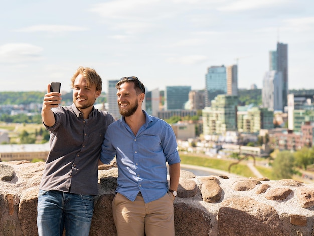 Lächelnde junge kaukasische Freunde machen Selfie vor der Skyline der Stadt als Reise- und Freundschaftskonzept