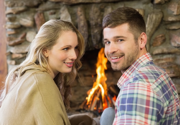 Lächelnde junge Paare vor beleuchtetem Kamin