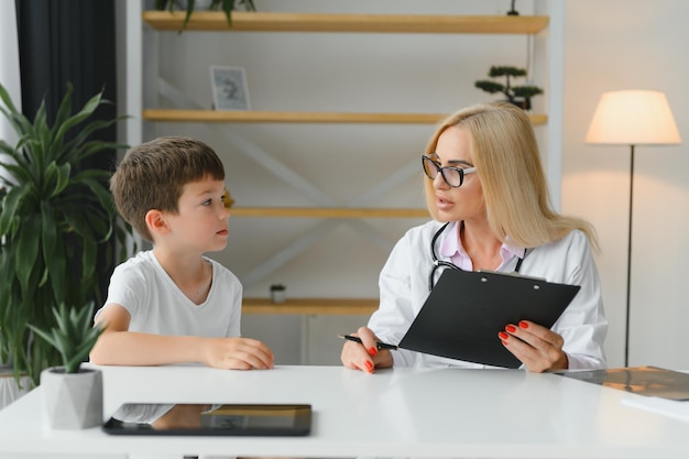 Lächelnde junge Ärztin oder Kinderärztin sprechen Trost kleiner Junge Patient bei der Beratung in einer Privatklinik Fürsorgliche Frau GP Unterstützung jubeln kleines Kind untersuchen konsultieren im Krankenhaus Gesundheitskonzept