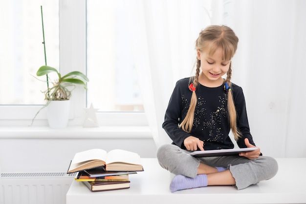lächelnde junge weibliche Kinder mit digitalem Tablet-Pad, die Online-E-Learning-Videos ansehen, um zu Hause Englisch zu lernen