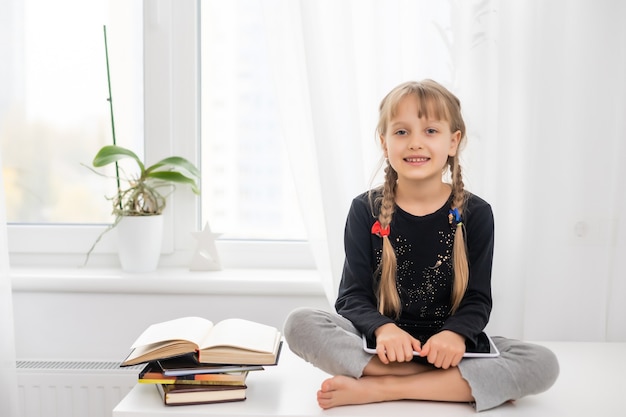 lächelnde junge weibliche Kinder mit digitalem Tablet-Pad, die Online-E-Learning-Videos ansehen, um zu Hause Englisch zu lernen