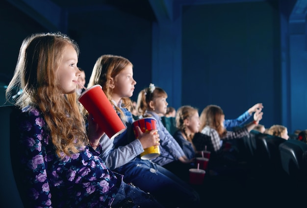 Lächelnde junge Zuschauer, die Popcorn essen und Karikatur im Kino aufpassen.