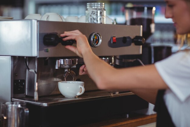 Lächelnde Kellnerin, die eine Tasse Kaffee macht