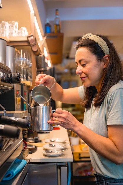 Lächelnde kellnerin in einer weiblichen cafeteria, die kaffee in einer kaffeemaschine zubereitet, covid-beschränkungen werden aufgehoben und die obligatorische verwendung von gesichtsmasken wird aufgehoben